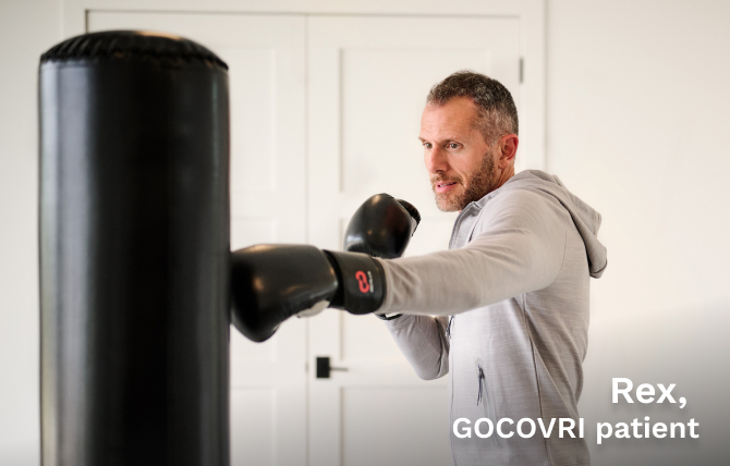 Rex, a GOCOVRI patient, hitting a heavy bag while wearing his boxing gloves. 